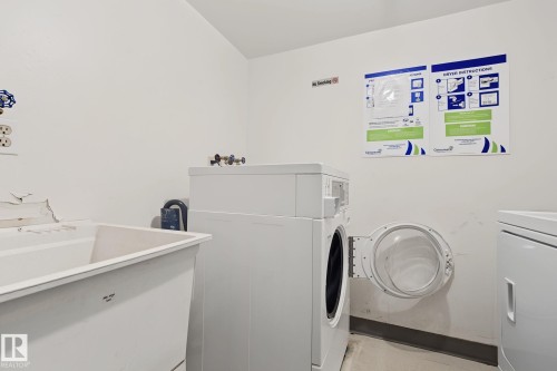 Laundry room featuring a utility sink, a front-loading washing machine, and a dryer - #6E 11608 28 Av Nw Nw, Edmonton, AB - Indoor Photo Showing Laundry Room