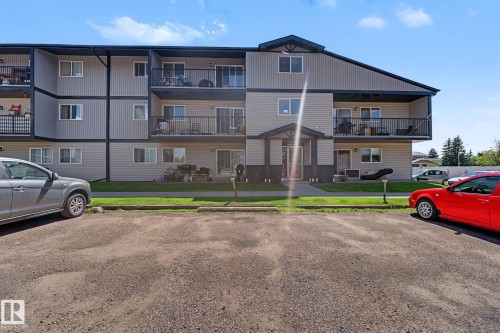 Multi-level building with beige siding and dark trim, featuring individual balconies with black railings - #6E 11608 28 Av Nw Nw, Edmonton, AB - Outdoor With Balcony