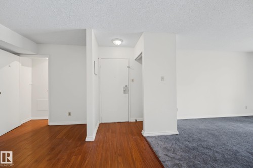 Entryway featuring wood-finish flooring, a flush-mount ceiling light, white walls, and a white entry door with a silver-tone lockset - #6E 11608 28 Av Nw Nw, Edmonton, AB - Indoor Photo Showing Other Room
