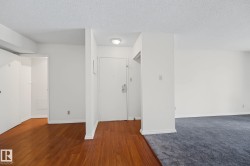 Entryway featuring wood-finish flooring, a flush-mount ceiling light, white walls, and a white entry door with a silver-tone lockset - 