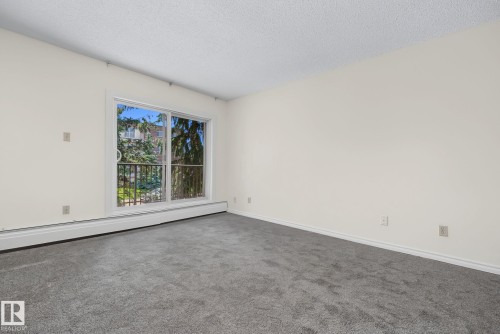 Sliding glass doors opening to a private balcony with black metal railing - #6E 11608 28 Av Nw Nw, Edmonton, AB - Indoor Photo Showing Other Room