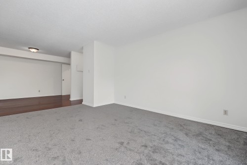 Spacious interior featuring light gray carpeting and white walls - #6E 11608 28 Av Nw Nw, Edmonton, AB - Indoor Photo Showing Other Room