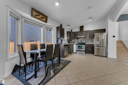 Kitchen with dark wood cabinetry, stainless steel appliances, and tile flooring - 1316 35 Street, Edmonton, AB 