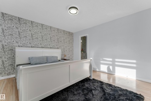 Bedroom featuring a floral accent wall and wood-finish flooring - 1316 35 Street, Edmonton, AB 