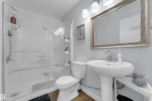 Pedestal sink with chrome faucet, framed mirror, and a three-light vanity fixture - 1316 35 Street, Edmonton, AB 
