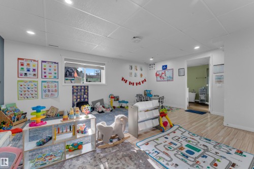 Spacious room featuring a drop ceiling with recessed lighting, a window providing natural light, and a mix of wood-finish flooring and patterned carpeting - 1316 35 Street, Edmonton, AB 