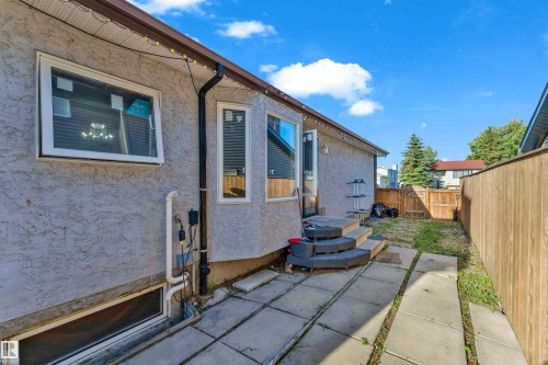 Rear exterior featuring stucco siding, multiple windows, and a wood privacy fence enclosing the yard - 1316 35 Street, Edmonton, AB 