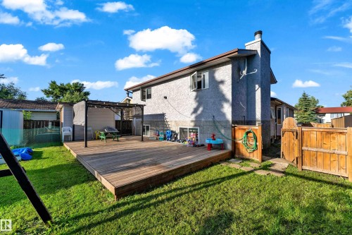 Spacious backyard featuring a large wooden deck, expansive green lawn, and privacy fencing - 1316 35 Street, Edmonton, AB 