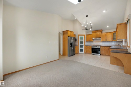 Kitchen area featuring wood-finish cabinetry, stainless steel appliances, and tile flooring - 15227 47 Street, Edmonton, AB 