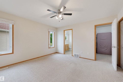 Spacious room featuring light-toned carpeting, neutral wall finishes, and wood-trimmed windows with blinds - 15227 47 Street, Edmonton, AB 