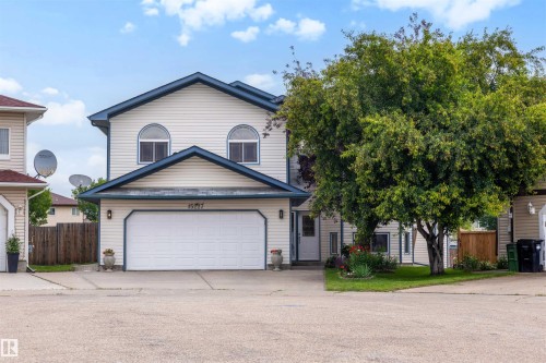 Residential facade with light-colored siding and dark trim, featuring an integrated two-car garage - 15227 47 Street, Edmonton, AB 