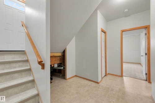 Entryway featuring staircase with tiled treads and wood railing - 15227 47 Street, Edmonton, AB 