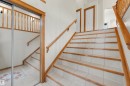 Staircase with light-toned tile treads and wood risers, complemented by a wood handrail - 15227 47 Street, Edmonton, AB 