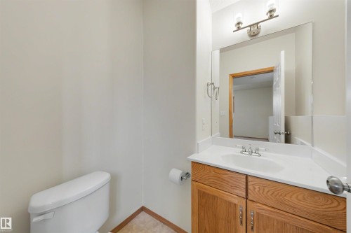 Bathroom vanity featuring wood cabinetry, a white countertop with an integrated sink, and an overhead light fixture - 15227 47 Street, Edmonton, AB 