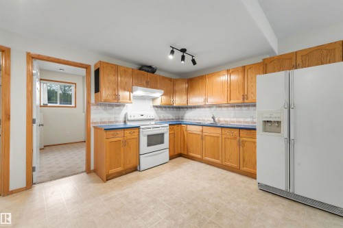 Kitchen featuring wood cabinetry, blue countertops, white appliances, and track lighting - 15227 47 Street, Edmonton, AB 