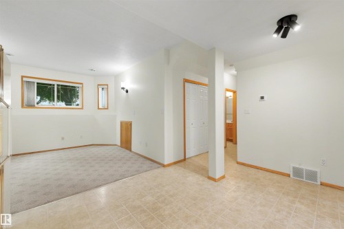 Spacious room featuring a large window, neutral carpeting, and tiled flooring - 15227 47 Street, Edmonton, AB 