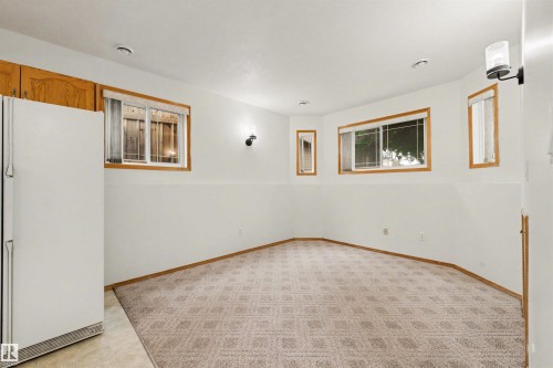 Carpeted floor with geometric pattern, wood trim accents, multiple windows, built-in cabinetry, and wall-mounted lighting fixtures - 15227 47 Street, Edmonton, AB 