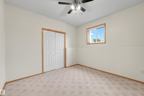 Carpeted room with a ceiling fan, baseboard trim, and a window with wood trim - 15227 47 Street, Edmonton, AB 