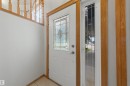 Entryway featuring a white door with decorative glass insert, a full-length sidelight, and wood-finish trim - 15227 47 Street, Edmonton, AB 