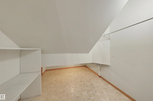Room with sloped ceilings, light-toned tile flooring, built-in shelving, and a hanging rod - 15227 47 Street, Edmonton, AB 