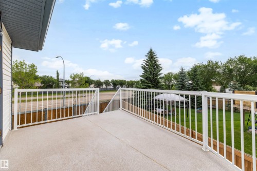 Expansive outdoor deck featuring a light-colored textured surface and white railing - 15227 47 Street, Edmonton, AB 