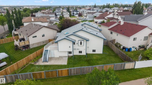 Spacious backyard featuring a manicured lawn, concrete patio, exterior staircase, and perimeter fencing - 15227 47 Street, Edmonton, AB 
