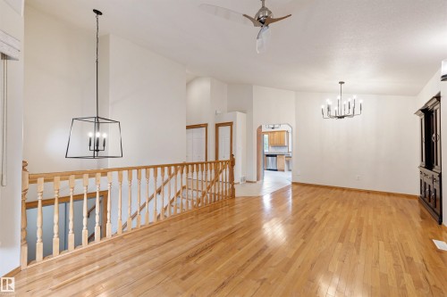 Hardwood flooring extends throughout this expansive interior, featuring vaulted ceilings and a traditional wood banister - 15227 47 Street, Edmonton, AB 