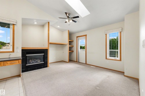 Carpeted living area featuring a vaulted ceiling with a skylight and ceiling fan - 15227 47 Street, Edmonton, AB 