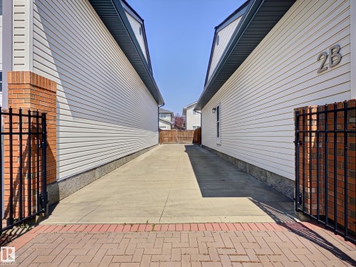 Paved driveway between two structures, featuring white siding and dark soffits - 17 10 Blackburn Drive, Edmonton, AB 