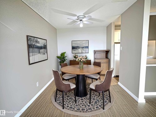Dining area featuring wood-finish flooring, light grey walls, and a ceiling fan with integrated lighting - 1105 11007 83 Avenue, Edmonton, AB 