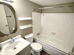 Full bathroom featuring a white vanity with integrated sink, chrome faucet, oval mirror, and a full-size bathtub with white subway tile surround - 