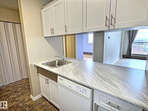 Kitchenette featuring white shaker-style cabinetry, a stainless steel sink, and a white dishwasher - 1105 11007 83 Avenue, Edmonton, AB 