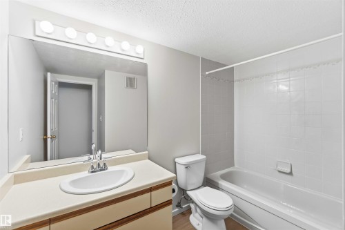 Bathroom featuring a vanity with an integrated sink, a large wall-mounted mirror, and a five-light vanity fixture - #304 4924 19 Av Nw, Edmonton, AB 
