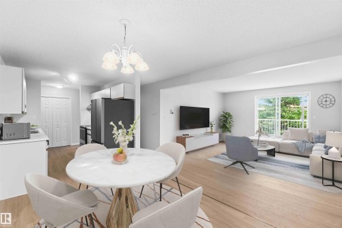 Open-concept living space featuring light wood-finish flooring, white walls, and a recessed kitchen - #304 4924 19 Av Nw, Edmonton, AB 