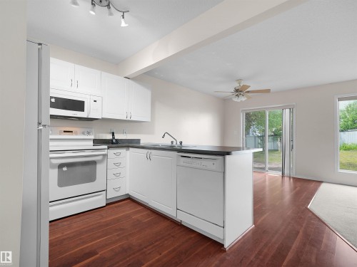 Kitchen featuring white cabinetry, dark countertops, and stainless steel appliances - 16106 131A Street, Edmonton, AB 