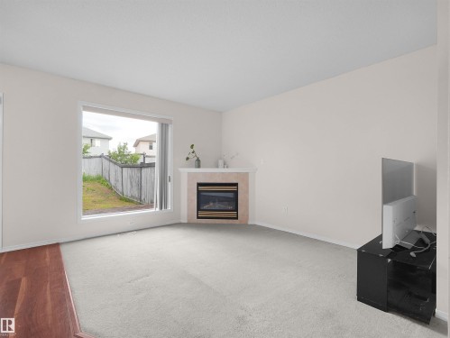 Living room with a large window, light-colored walls, and carpeting - 16106 131A Street, Edmonton, AB 