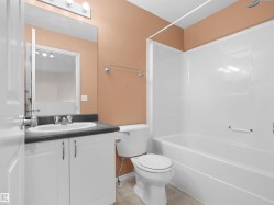 Bathroom with white vanity cabinetry, dark countertop, and a white integrated sink - 