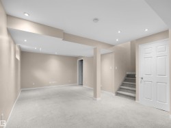 Carpeted lower-level room featuring recessed ceiling lighting, a staircase with carpeted treads, painted walls, and white trim - 