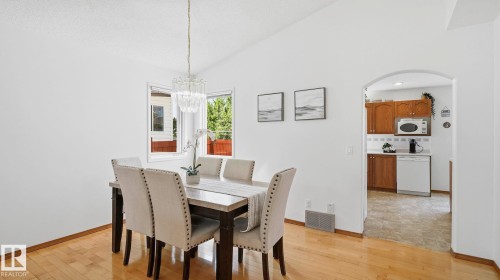 Dining area featuring wood-finish flooring, vaulted ceiling, and a modern chandelier - 1225 Kane Wynd, Edmonton, AB 
