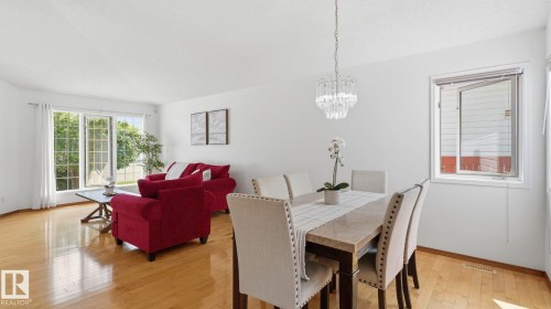 Open-concept living and dining areas featuring wood-finish flooring, white walls, and bright natural light from multiple windows - 1225 Kane Wynd, Edmonton, AB 