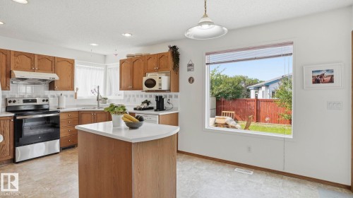 Kitchen featuring wood cabinetry, white countertops, tile backsplash, and stainless steel appliances - 1225 Kane Wynd, Edmonton, AB 