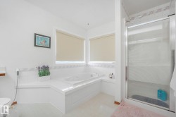 Built-in corner soaking tub, separate glass-enclosed shower, dual windows with roller shades, and tiled flooring - 