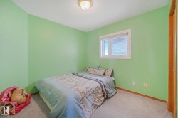 Wall-mounted lighting fixture, window with horizontal blinds, wood-finish door, and carpeted flooring - 