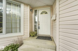 White paneled door with an arched transom window, side-light window panels, and a wall-mounted exterior light fixture - 
