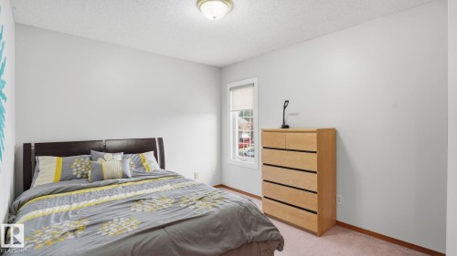 Bright bedroom featuring a single window with roller shade, neutral wall paint, and beige carpet flooring - 1225 Kane Wynd, Edmonton, AB 