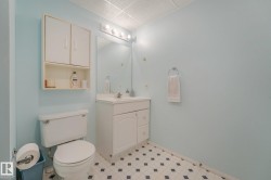 White vanity with integrated sink, overhead lighting, wall-mounted mirror, and patterned flooring - 
