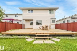 Expansive wood deck with stairs, surrounded by a manicured lawn and privacy fencing - 