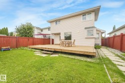 Expansive backyard featuring a wood deck with steps, a manicured lawn, and a privacy fence - 