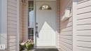 White paneled entry door with an arched transom window and sidelight - 1225 Kane Wynd, Edmonton, AB 