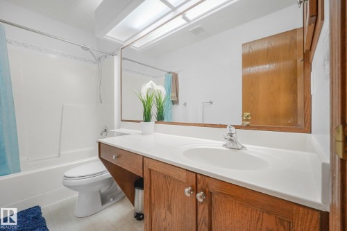 Built-in vanity with wood-finish cabinetry, solid surface countertop, and integrated sink - 1225 Kane Wynd Nw, Edmonton, AB - Indoor Photo Showing Bathroom